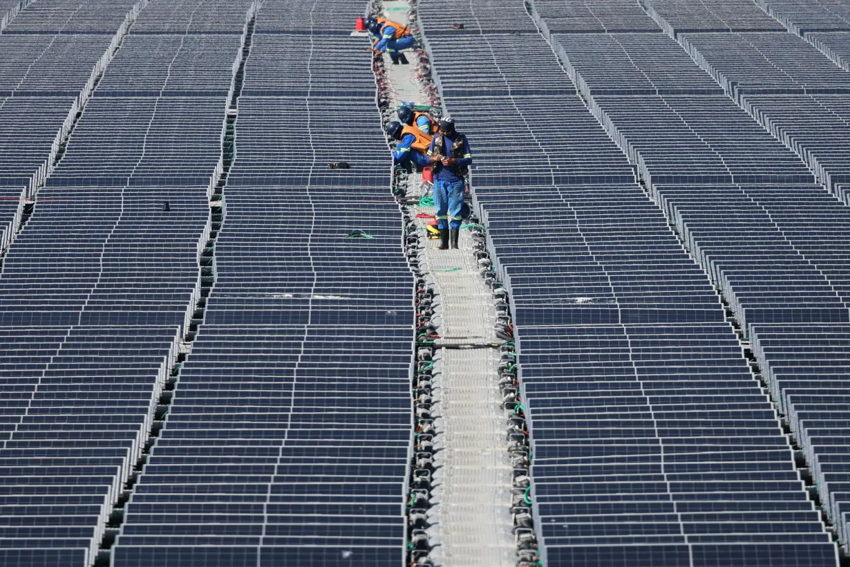 FILE PHOTO: Workers work at Brazil's biggest floating solar plant with 10,500 plates on the water surface at the Billings dam developed by Empresa Metropolitana de Aguas e Energia in Sao Paulo