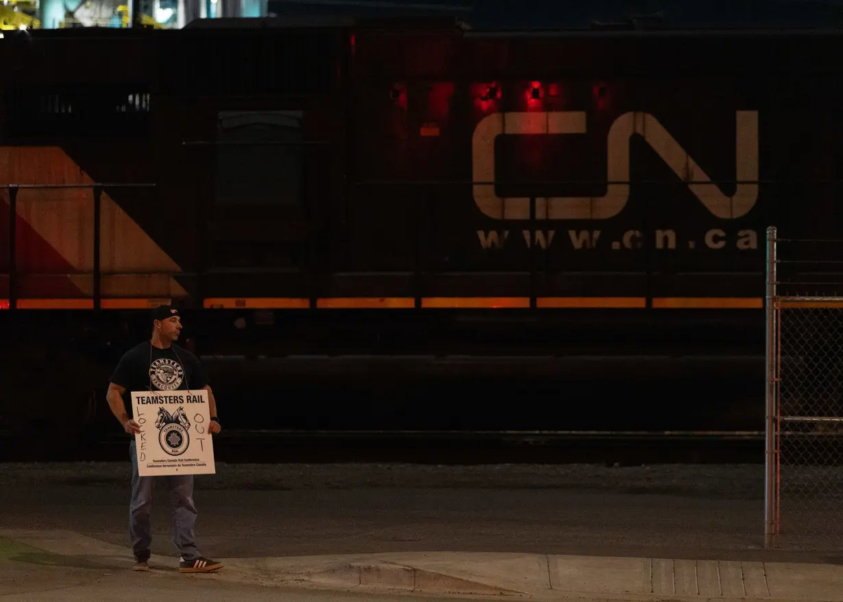 A Teamsters union member holds a picket sign at the entrance of CN Rail Lynn Creek Yard in North Vancouver, British Columbia, Canada.