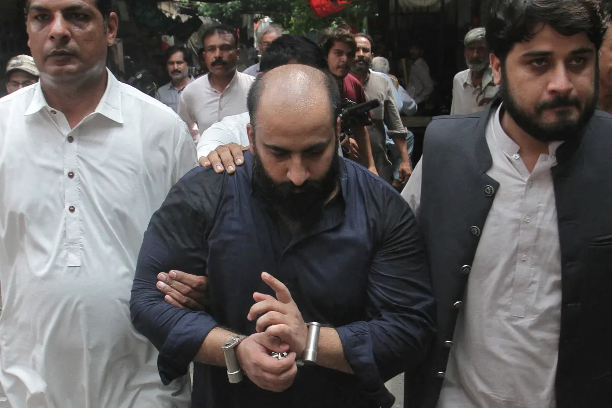 Farhan Asif is escorted by the members of FIA outside a court in Lahore