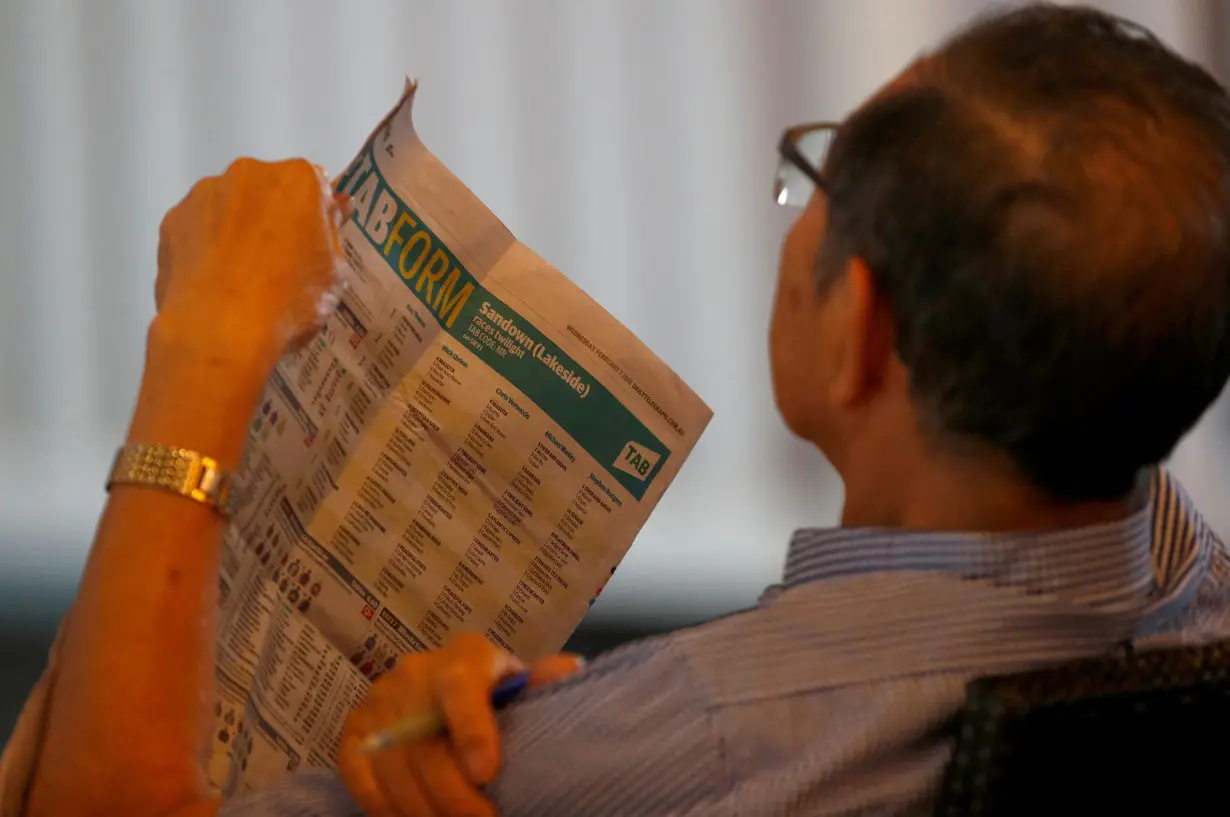 A man reads the TAB betting section on the newspaper on a TAB branch in Sydney