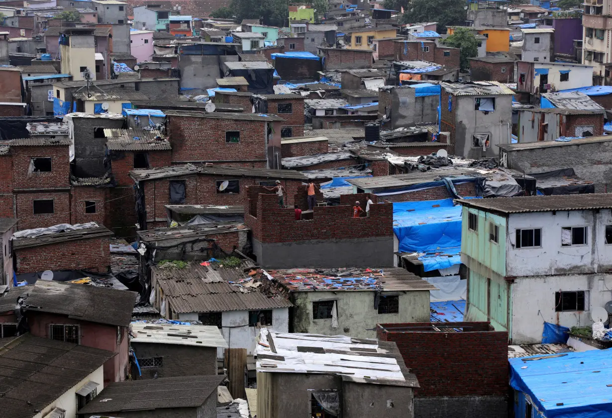 FILE PHOTO: Labourers construct a structure amidst shanties in Dharavi, Mumbai