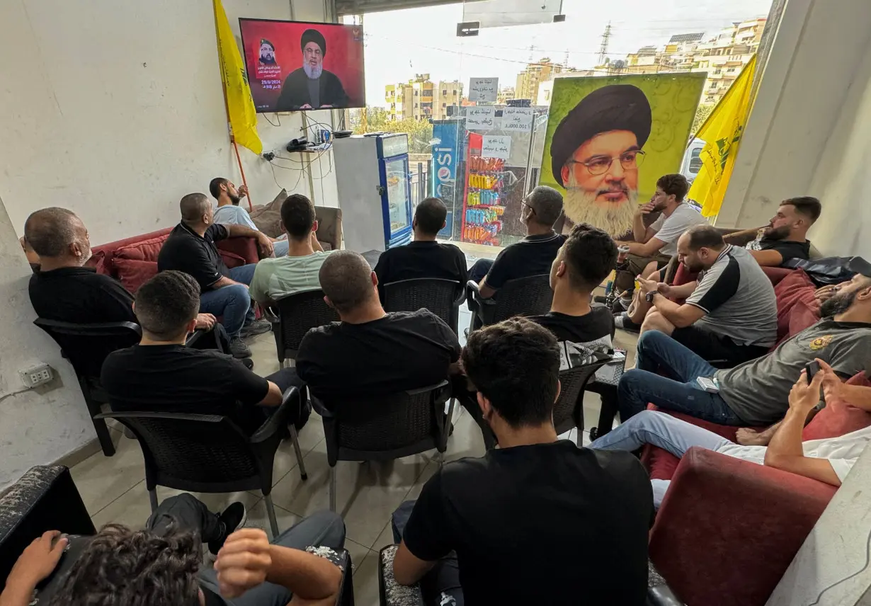 People watch Lebanon's Hezbollah leader Sayyed Hassan Nasrallah delivering a televised address, as they sit at a cafe in Sidon