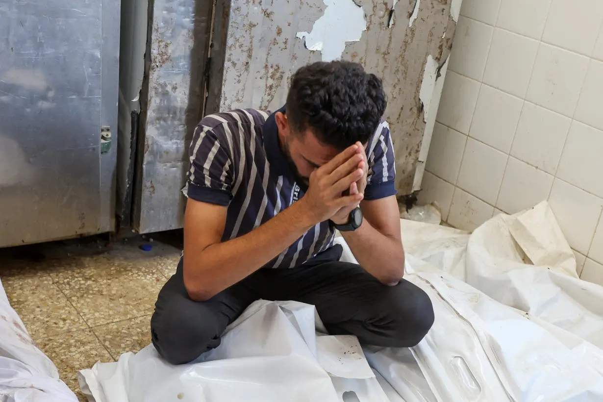 A mourner reacts over bodies of Palestinians killed in Israeli strikes, amid the Israel-Hamas conflict, at Al-Aqsa Martyrs Hospital in Deir Al-Balah in the central Gaza Strip