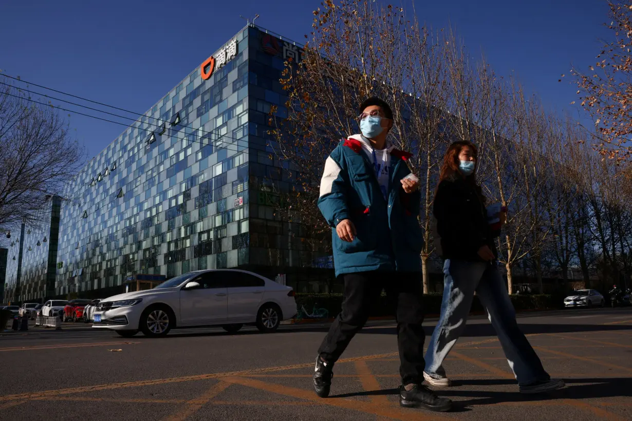 People walk past the headquarters of the Chinese ride-hailing service Didi in Beijing