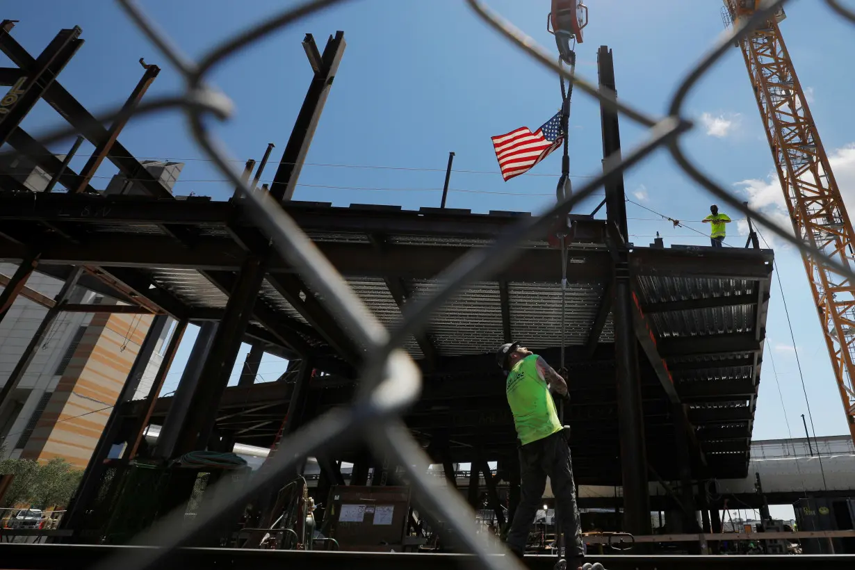 Construction workers install steel beams on high-rise building during a summer heat wave in Boston