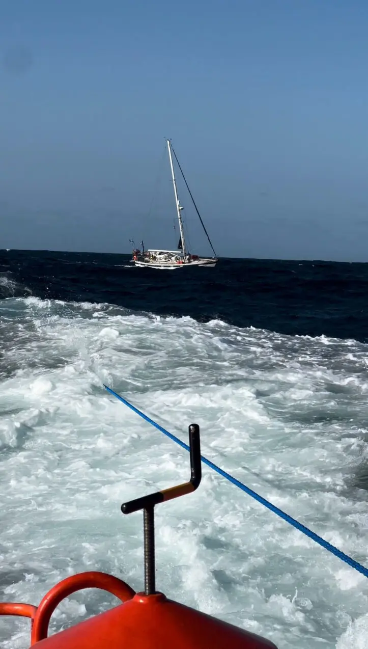 View shows a sailboat towed ashore by a Spanish Coast Guard vessel off the coast of Galicia