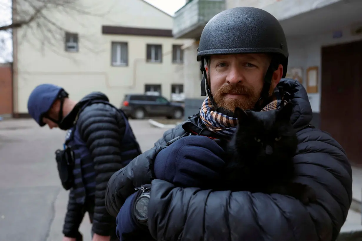 Reuters safety advisor Ryan Evans holds a cat during a news assignment, in Kramatorsk