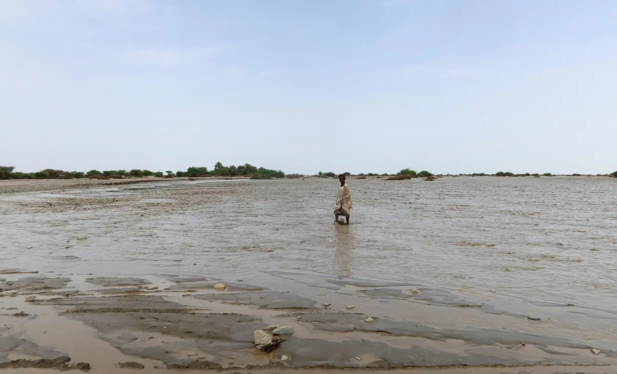 A person walks through flood water, in Port Sudan