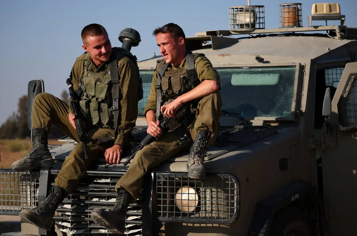 Israeli soldiers sit on a military vehicle near the Israel-Gaza border, amid the Israel-Hamas conflict