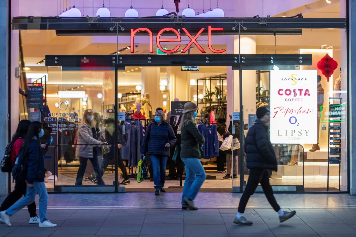 FILE PHOTO: People walk past a store of clothing retailer Next in London