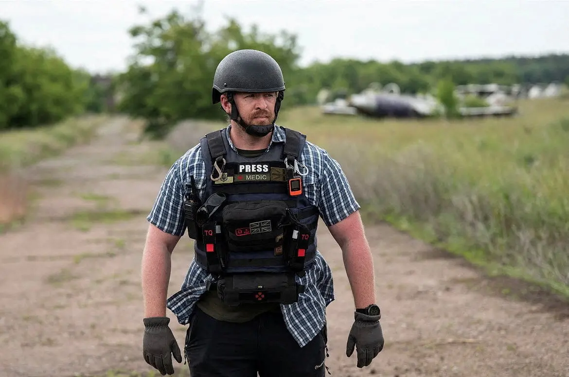 Reuters safety advisor Ryan Evans stands in a field while working with a news reporting team in Ukraine