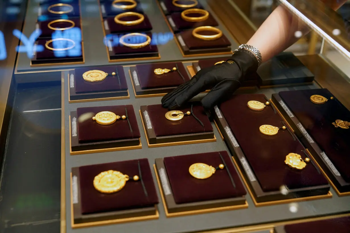 A salesperson poses with Heritage Gold jewellery at jeweller Chow Tai Fook's retail store in Shanghai