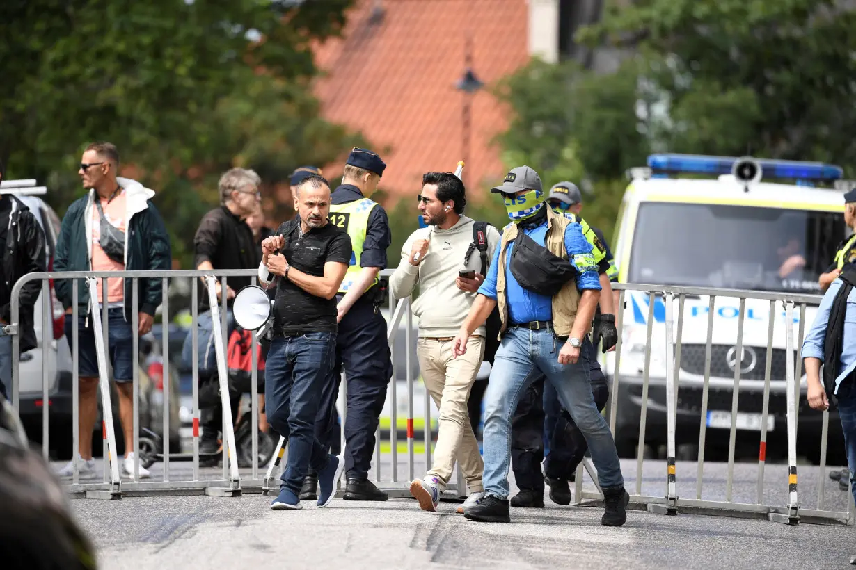 Protestor Salwan Momika is escorted by police to a location outside the Iraqi embassy, in Stockholm,