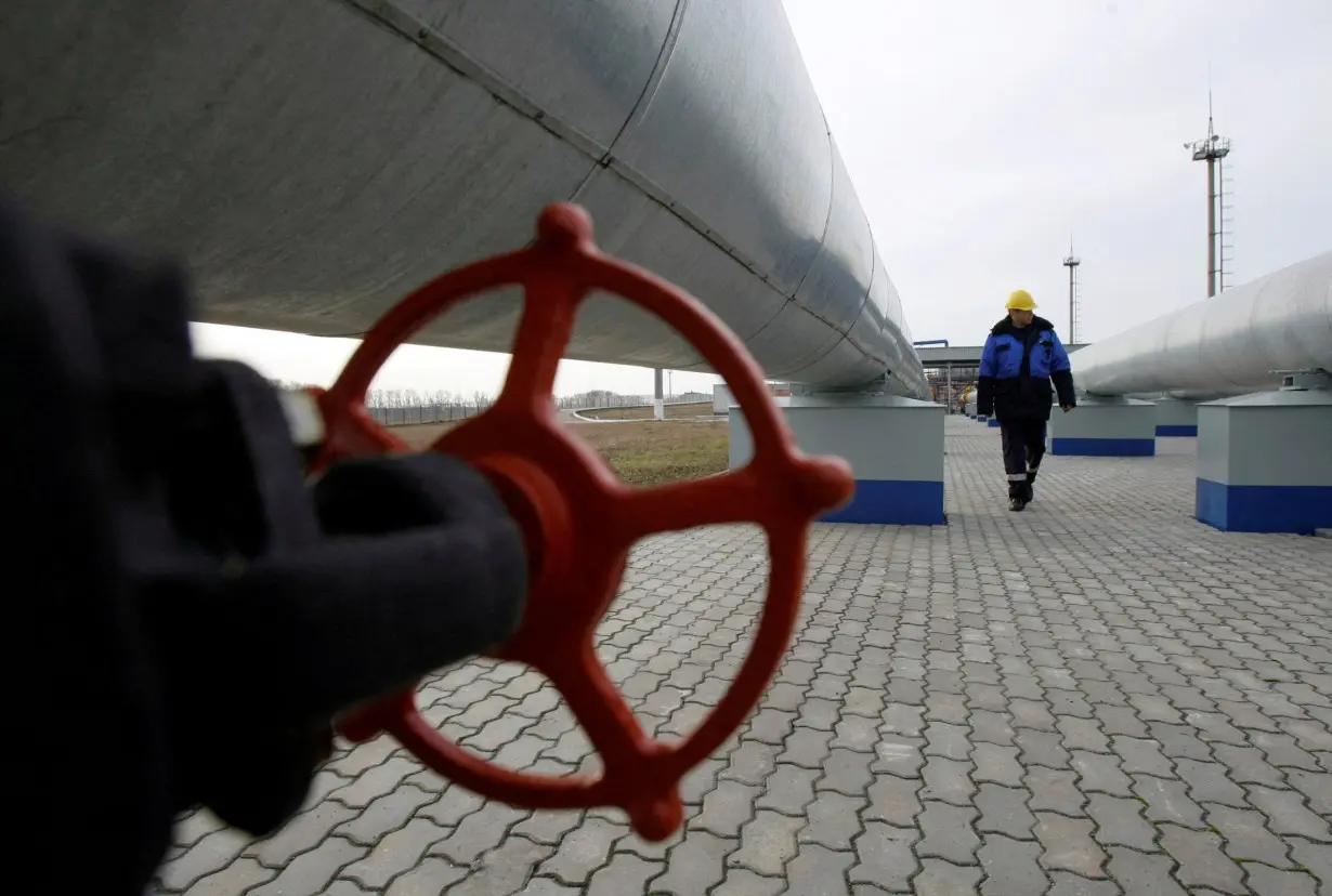 FILE PHOTO: A Gazprom worker walks next to pipelines at gas measuring station at Russian-Ukrainian border in Sudzha