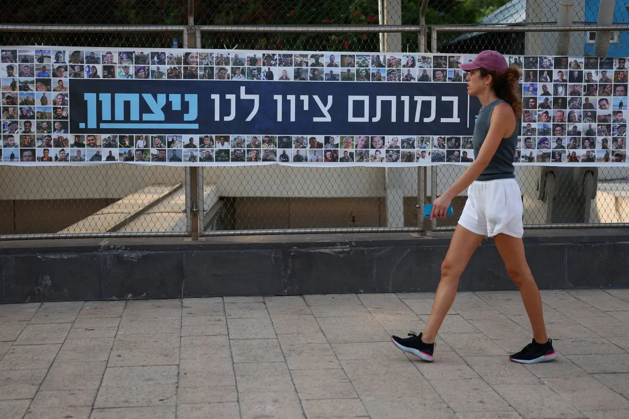 A woman walks past a banner depicting the faces of Israel's fallen soldiers, amid the ongoing conflict in Gaza between Israel and Hamas, in Tel Aviv