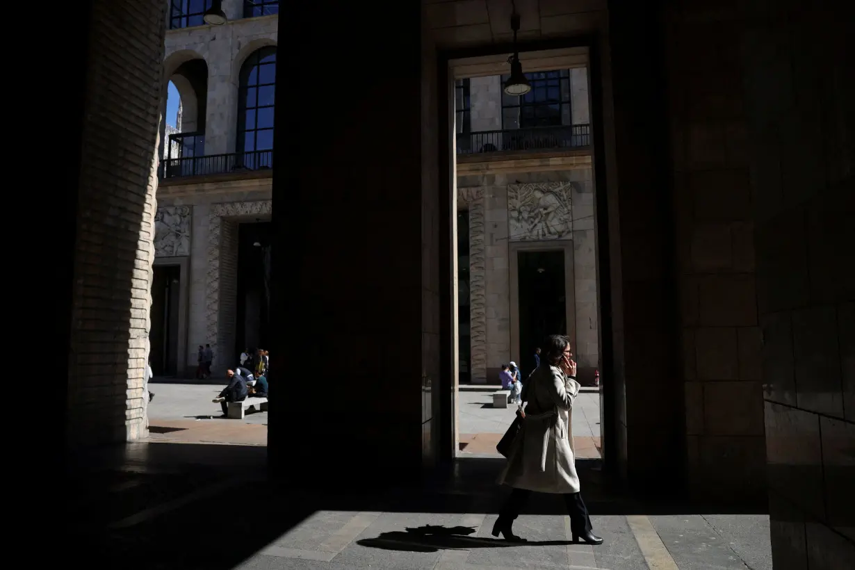 A woman walks under the Palazzo dell'Arengario, in Milan