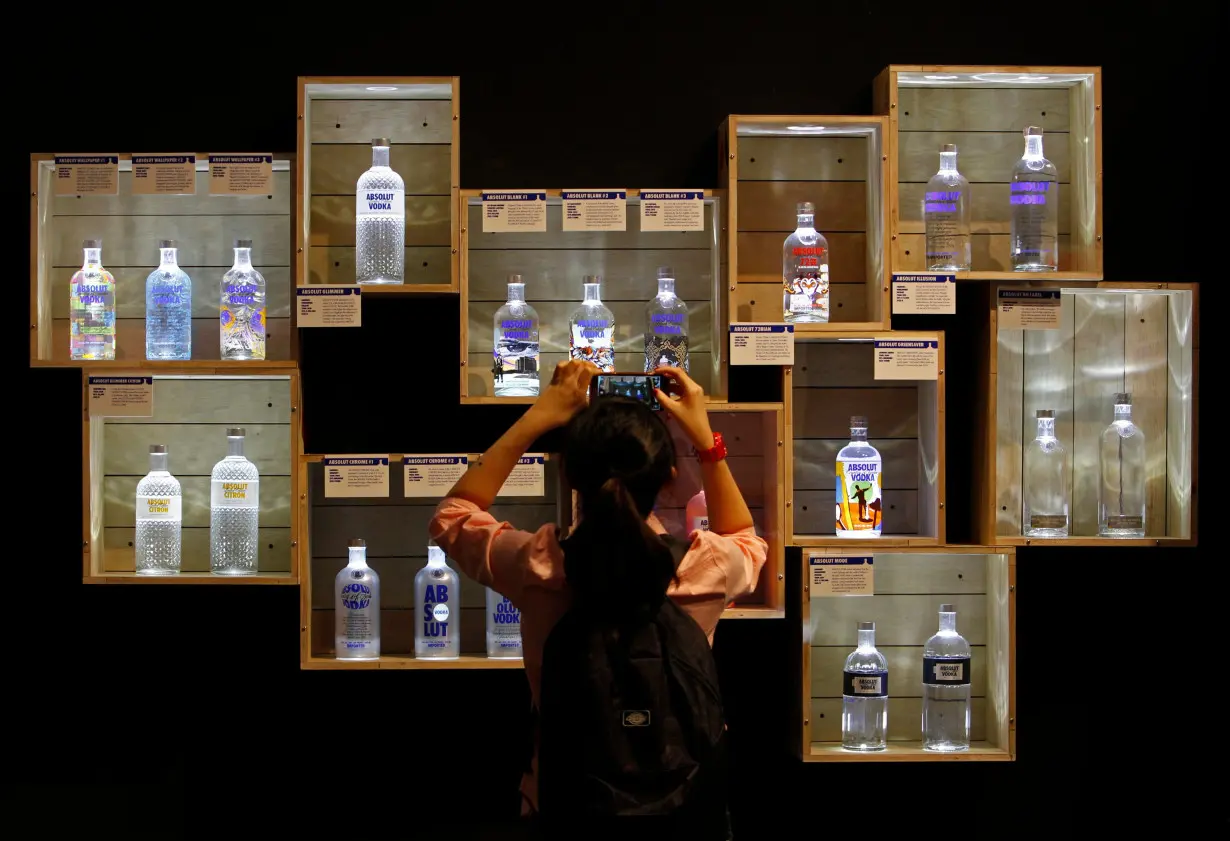 A visitor takes photos of limited edition Absolut Vodka bottles at the 