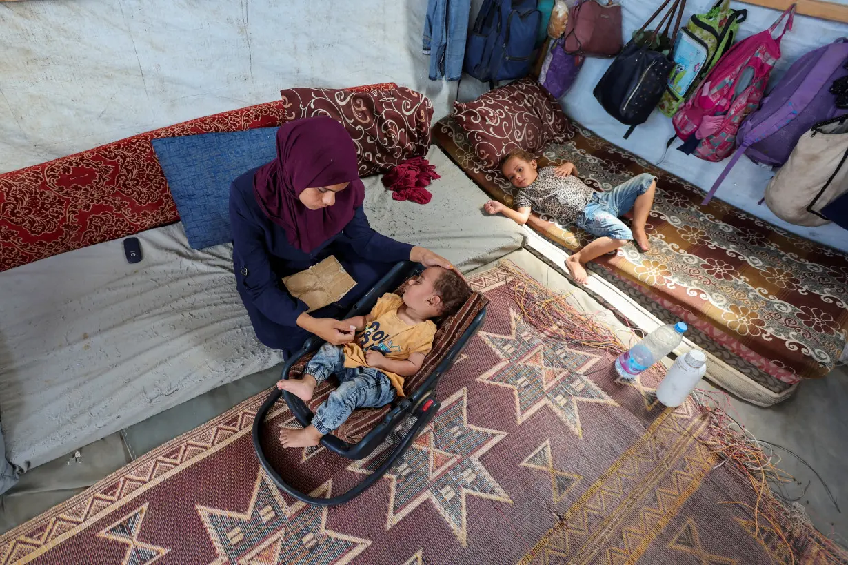 The mother of Palestinian boy Abdul Rahman Abu Al-Jidyan, who is the first person to contract polio in Gaza in 25 years, looks after him in their tent, in Deir Al-Balah, in the central Gaza Strip