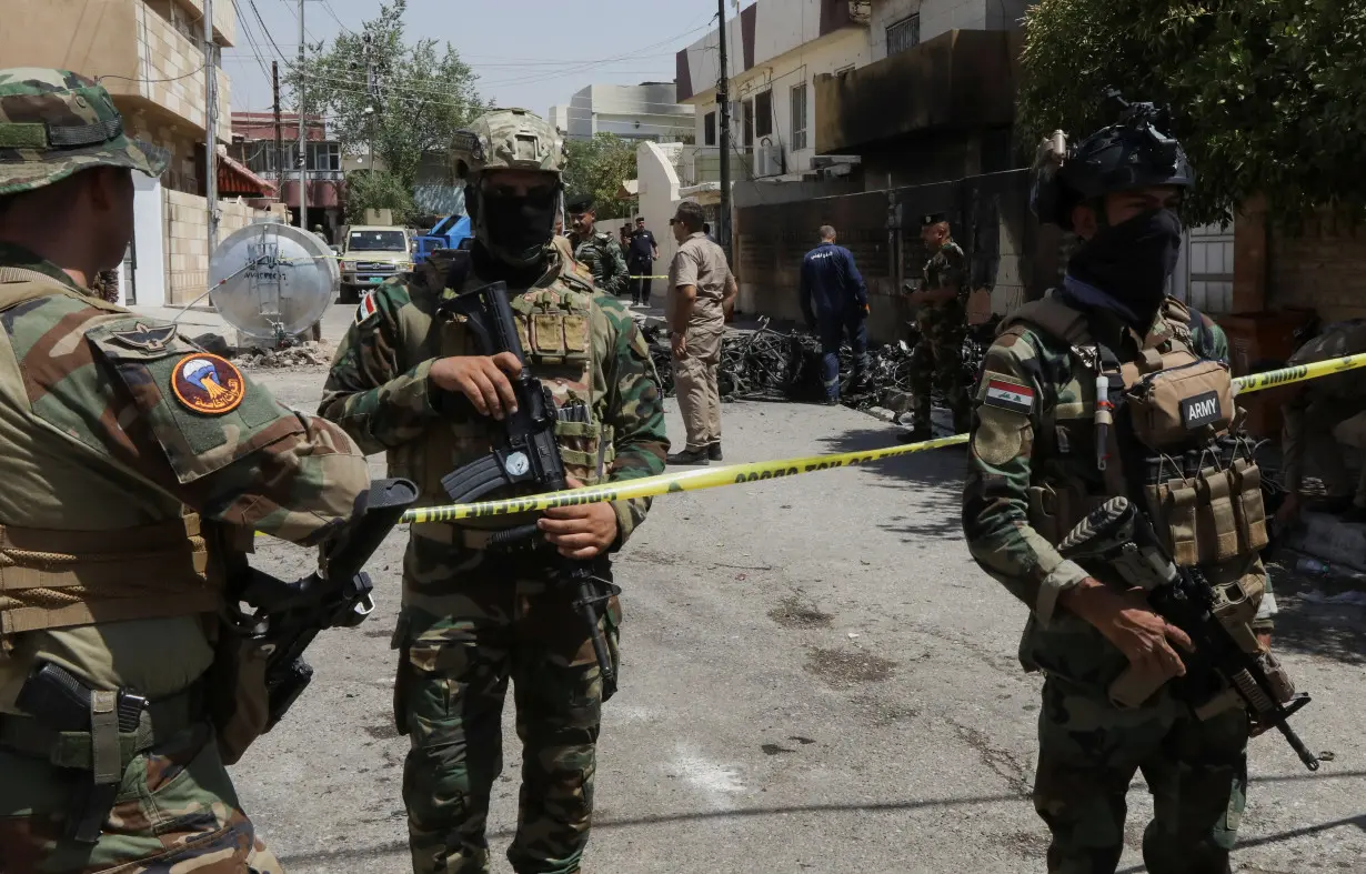 Members of Iraqi security forces stand near the debris of an armed drone shot down by Iraq's air defences in Kirkuk