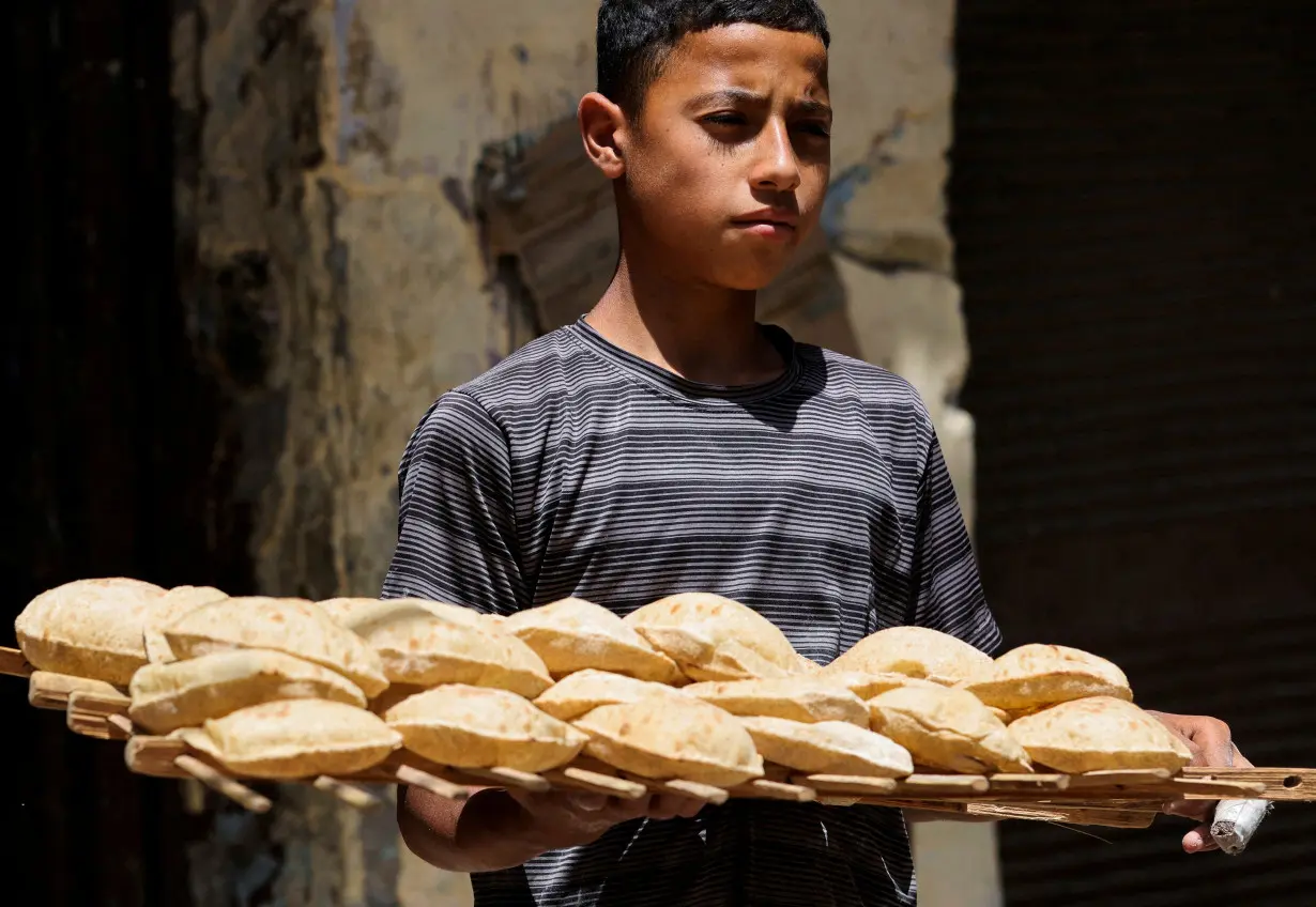 FILE PHOTO: A boy carries bread, at the vegetable market, after the price of subsidized bread jumped 300% to 20 piasters ($0.0042) from 5 piasters in Cairo