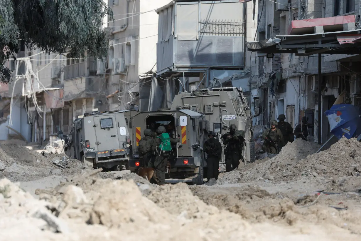 Israeli soldiers stand near a military vehicle during an Israeli raid in Nour Shams camp in Tulkarm