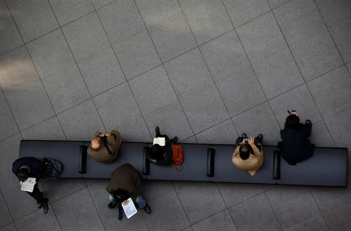 People sit on a bench at a convention centre in a financial district in Tokyo