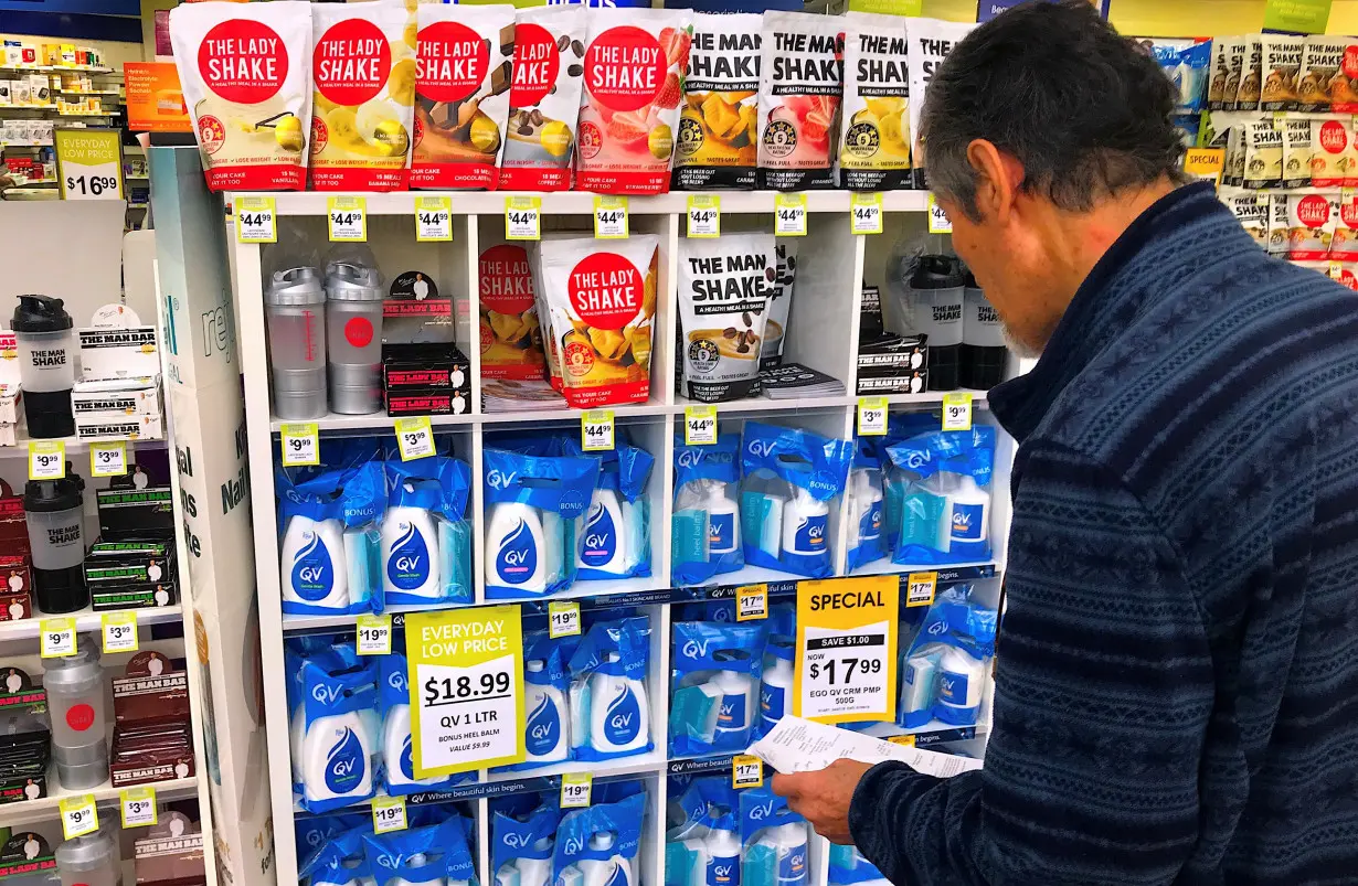 A customer looks at products marked with discounted prices on display at a chemist in a shopping mall in central Sydney