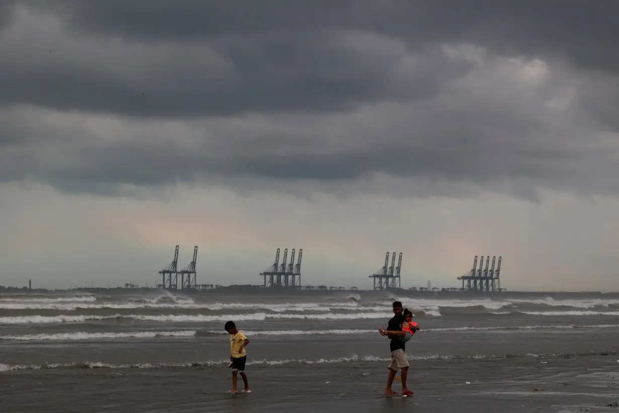 Children play, with the rainbow and rain clouds in the background, at Clifton Beach in Karachi