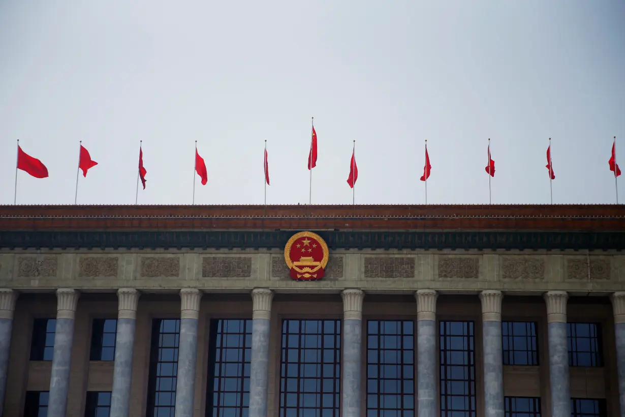 Flags flutter above the Chinese national emblem at the Great Hall of the People in Beijing