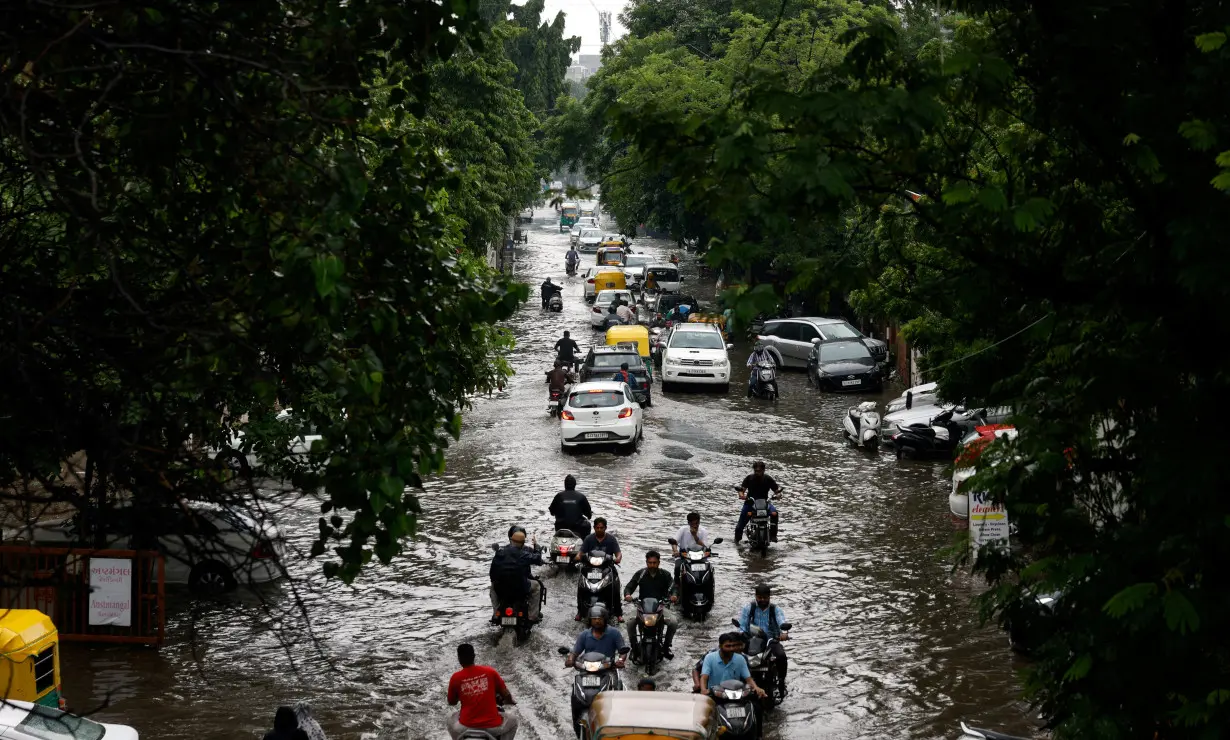 FILE PHOTO: Traffic moves through a flooded road after heavy rains in Ahmedabad