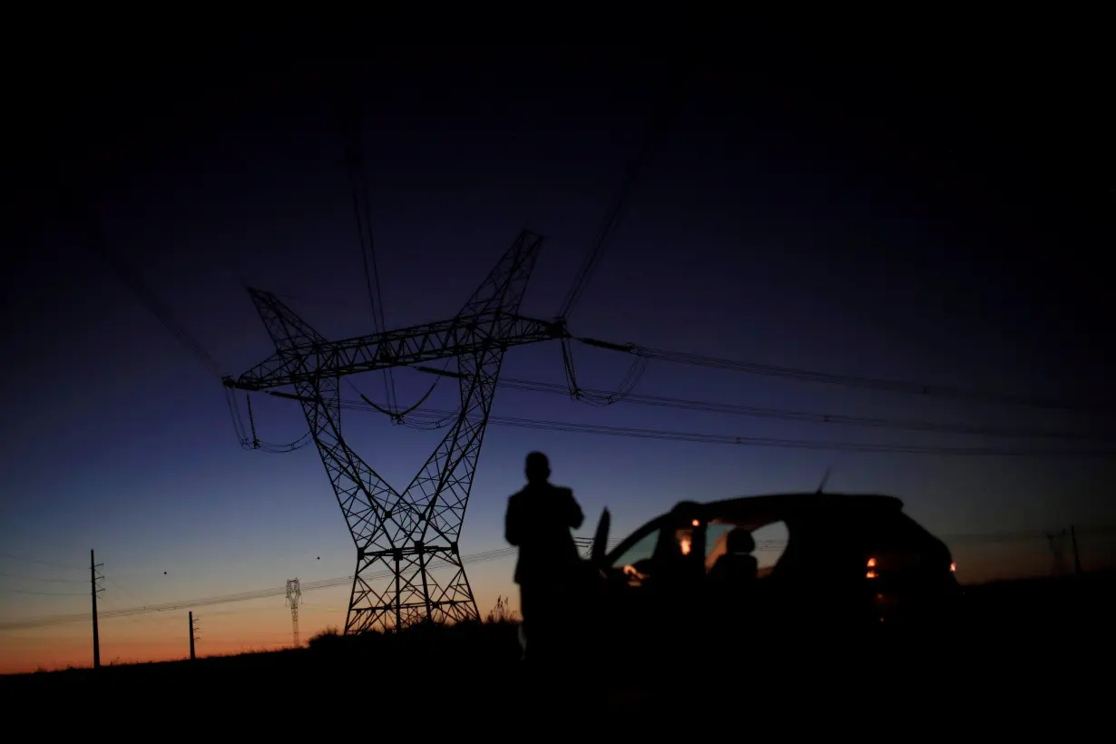 A man stands in front of power lines connecting pylons of high-tension electricity near Brasilia