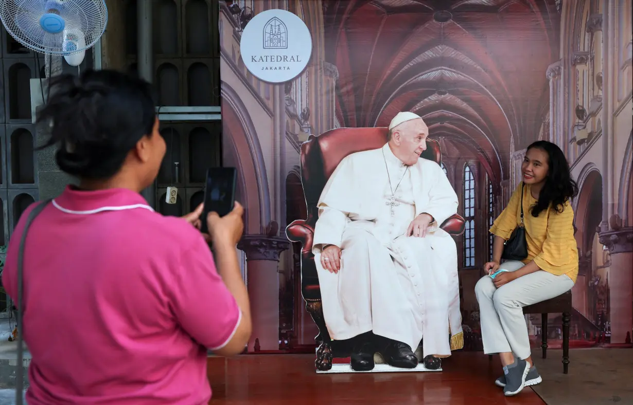 A person poses with a cutout depicting Pope Francis at Jakarta Cathedral ahead of his visit, in Jakarta