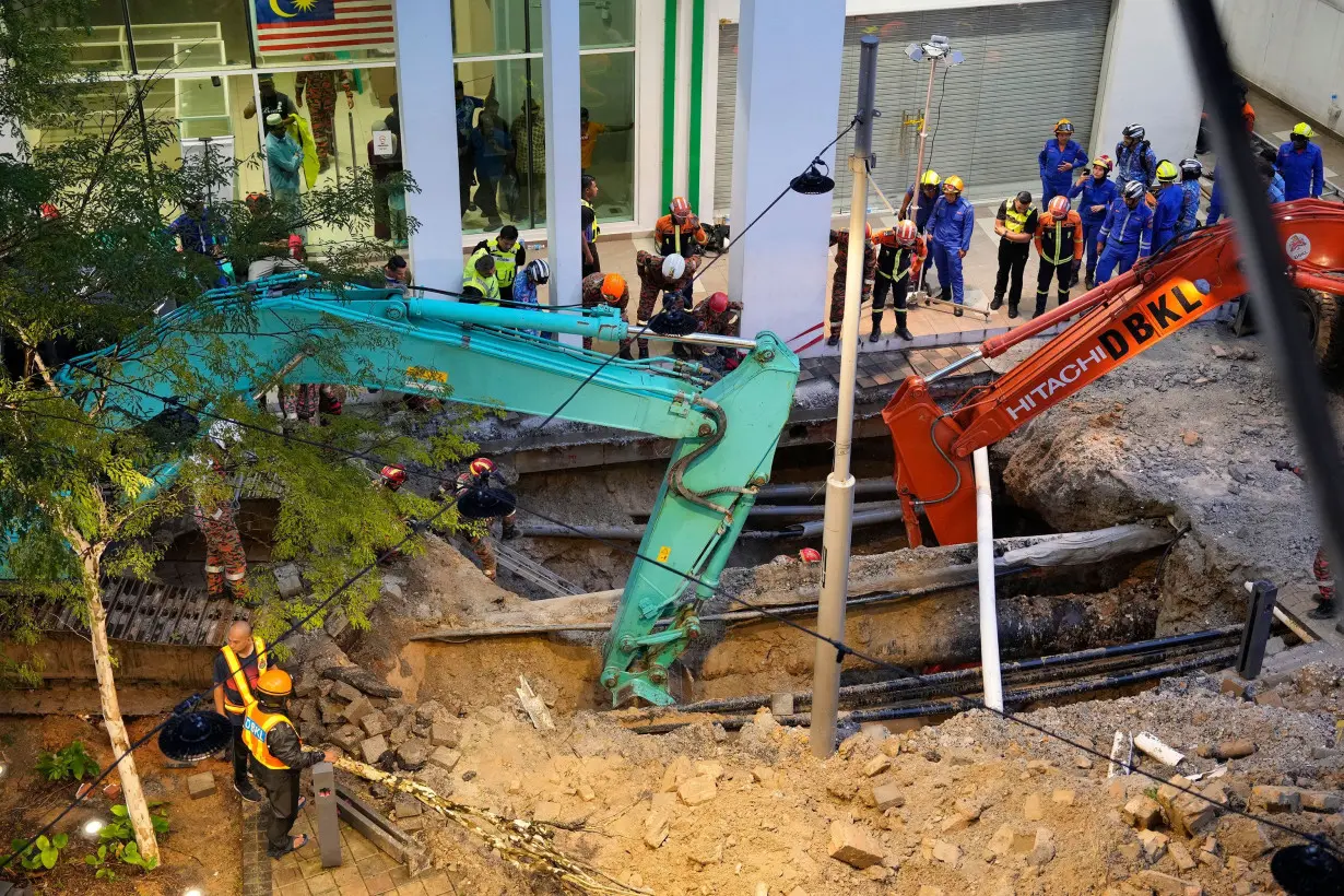 Fire and Rescue department workers search for a woman who fell into a sinkhole in Kuala Lumpur on August 23.