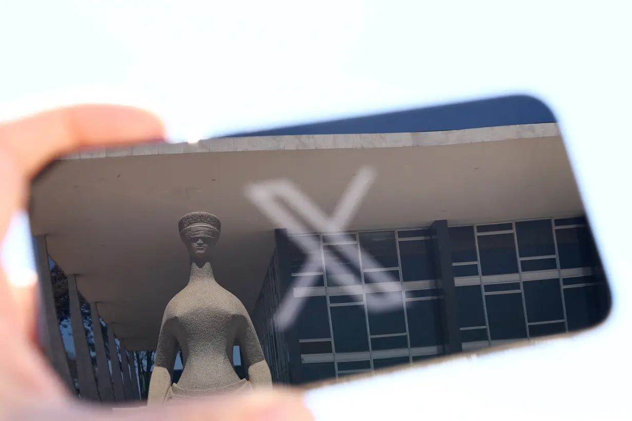 The logo of social media platform X is seen on a mobile phone next to a reflection of Brazil's Supreme Court in this illustration taken August 30, 2024, in Brasilia