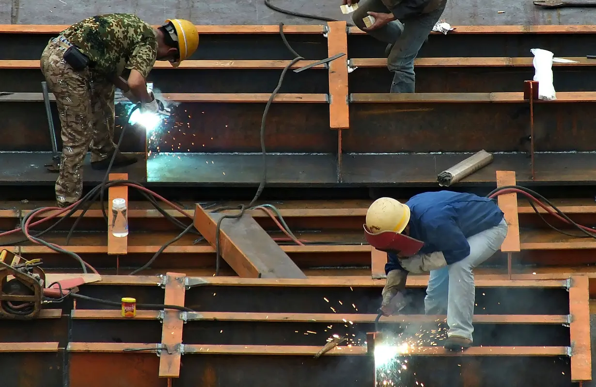 Workers weld steel frames as they work at a shipyard in Yichang