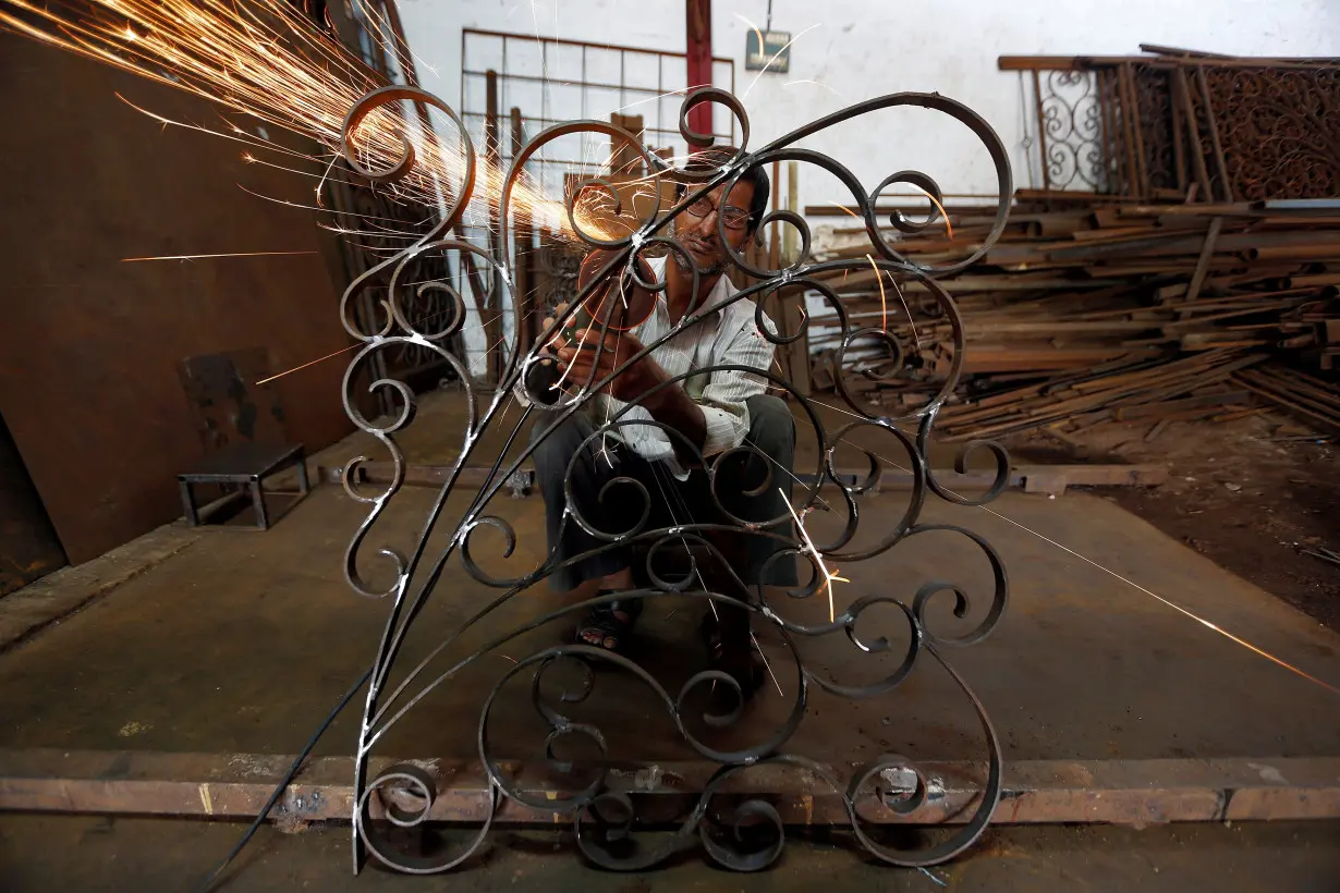 A worker grinds a metal window grill at a steel and iron manufacturing unit in Ahmedabad