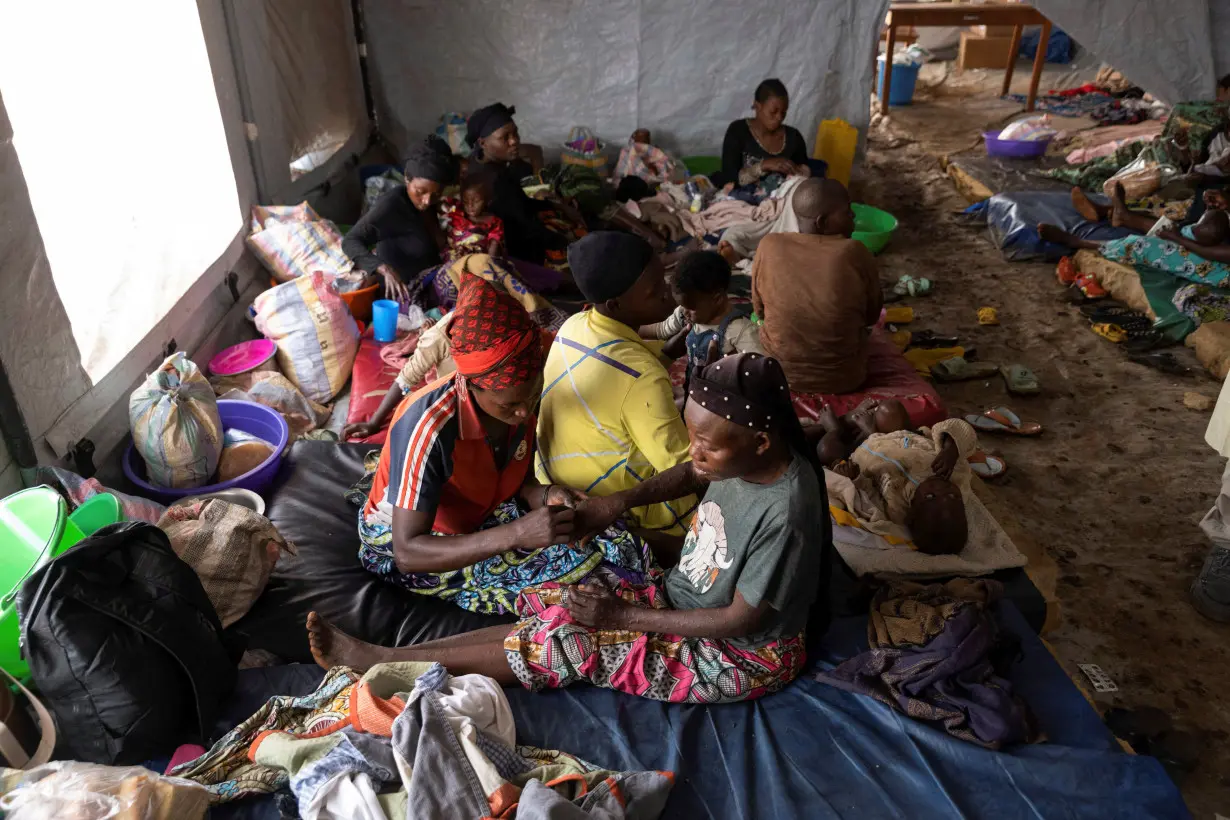 Nsimire Nakaziba pricks the rashes on her sister Sifa Mwakasisi to relieve pain inside a tent where she is undergoing treatment against mpox at the Kavumu hospital in Kabare territory