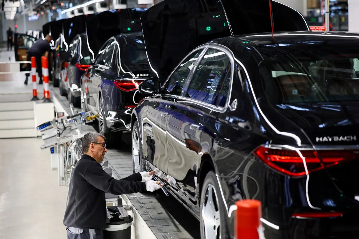 FILE PHOTO: A worker attaches a part to a Mercedes-Maybach car on a production line of 