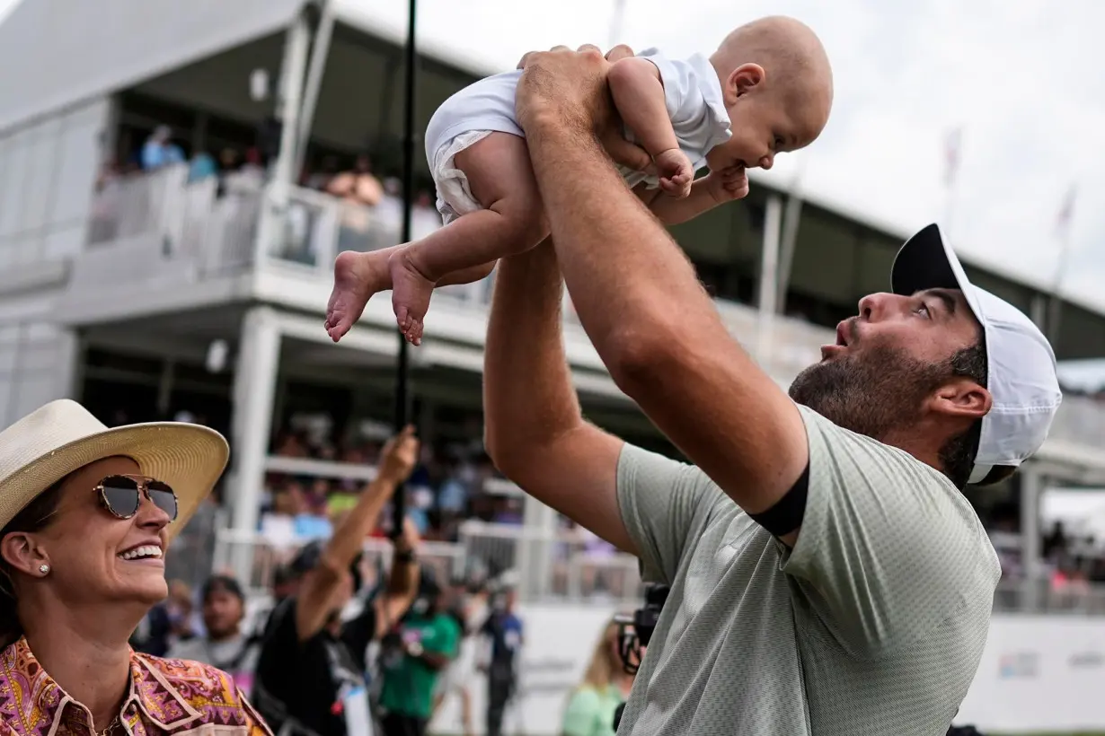 Scottie Scheffler holds his son Bennett as his wife Meredith looks on after winning the Tour Championship in Atlanta.