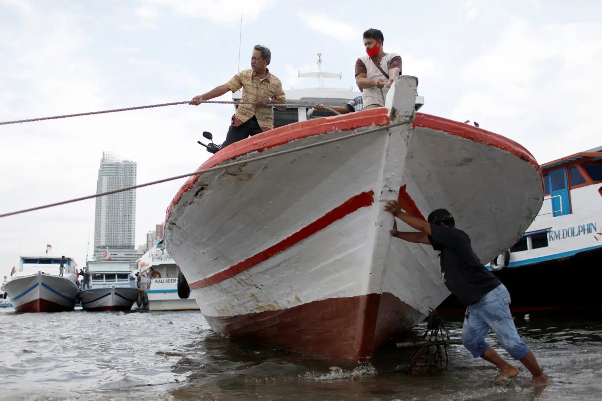 A man pushes a boat at Kali Adem port, north of Jakarta