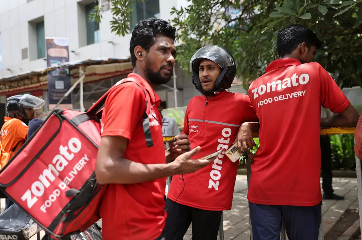 Gig workers wait in line to collect their delivery order outside a mall in Mumbai