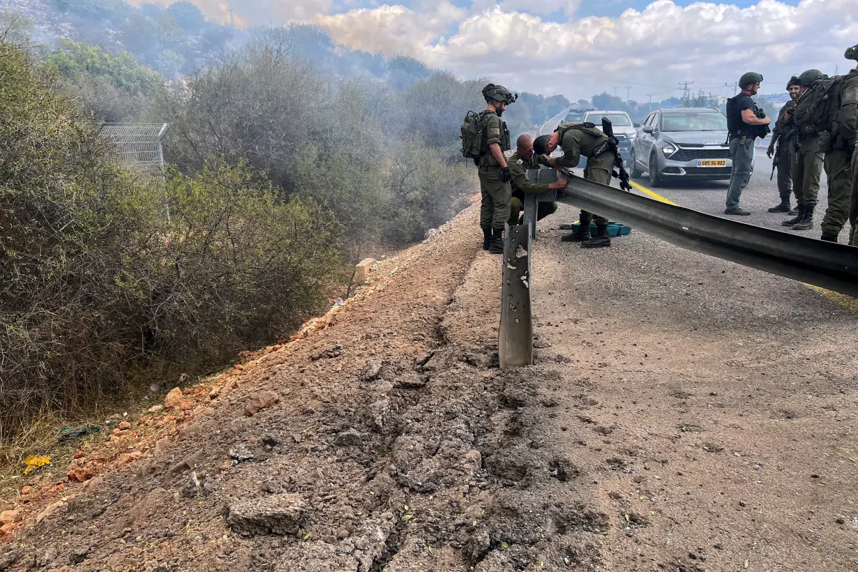 Israeli soldiers stand on a damaged road near the Israel-Lebanon border amid cross-border hostilities between Hezbollah and Israeli forces, in northern Israel