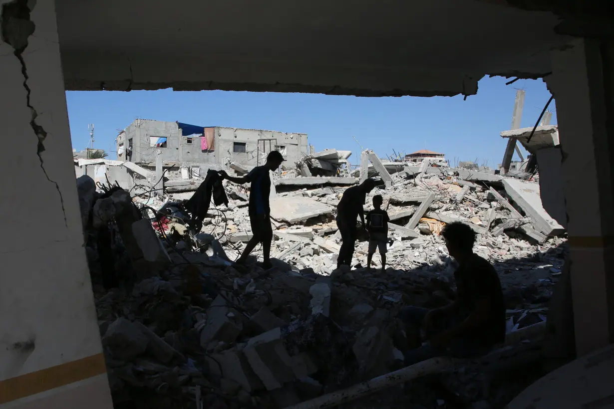 Palestinians remove the rubble of houses destroyed by Israeli strikes, in Khan Younis