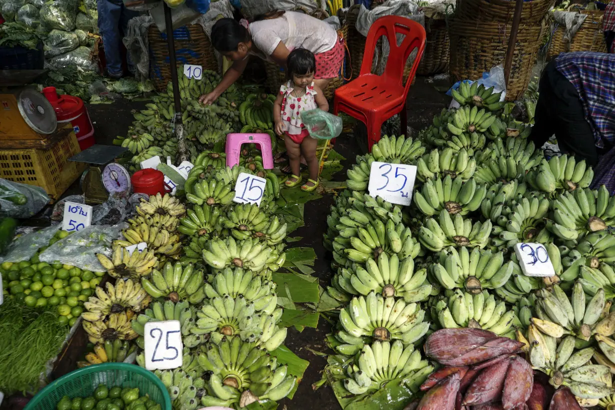 A mother and her daughter shop for bananas at a market in Bangkok