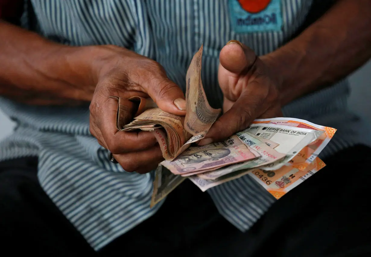 An attendant at a fuel station arranges Indian rupee notes in Kolkata