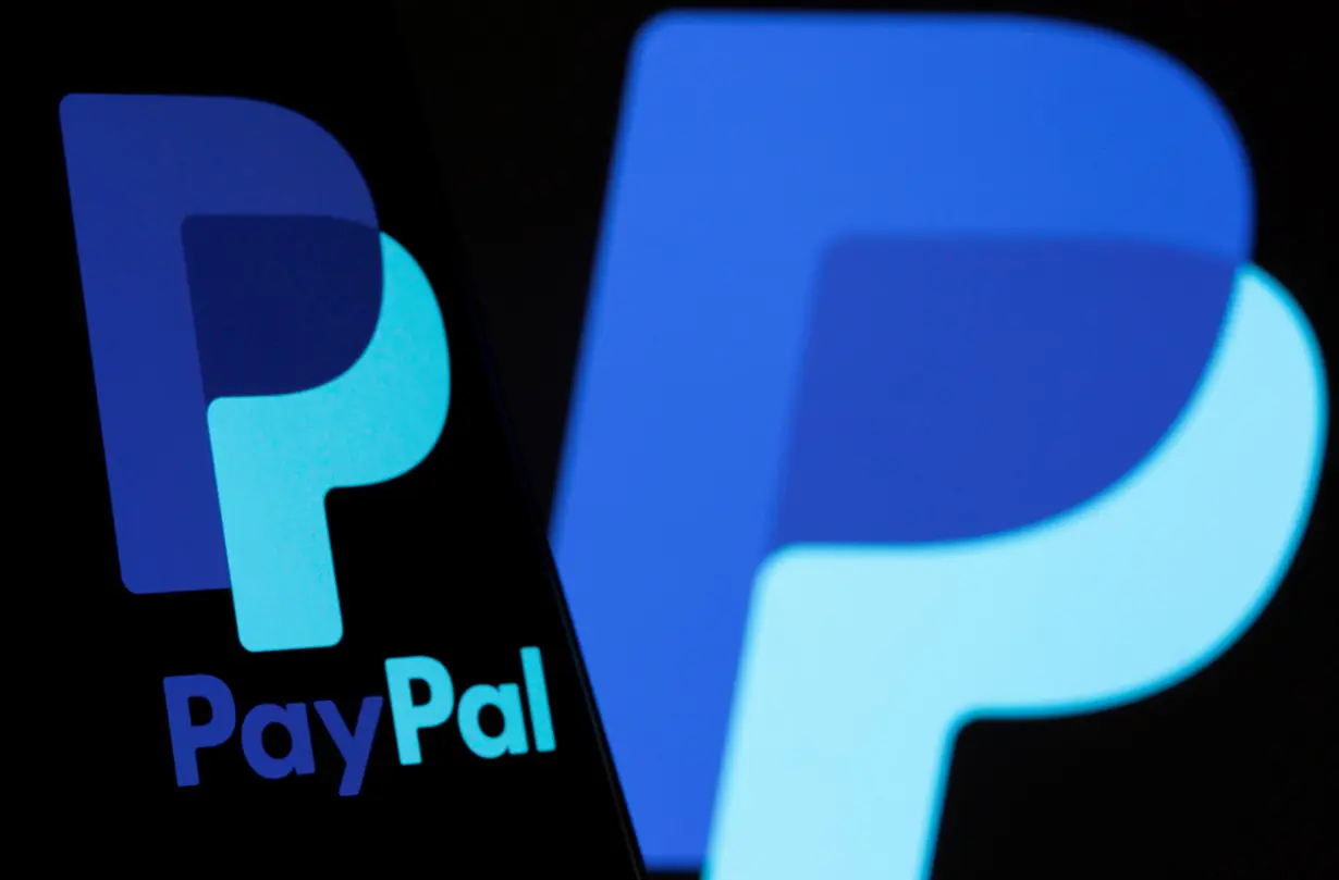 The PayPal logo is seen on a smartphone in front of the same logo displayed in this illustration