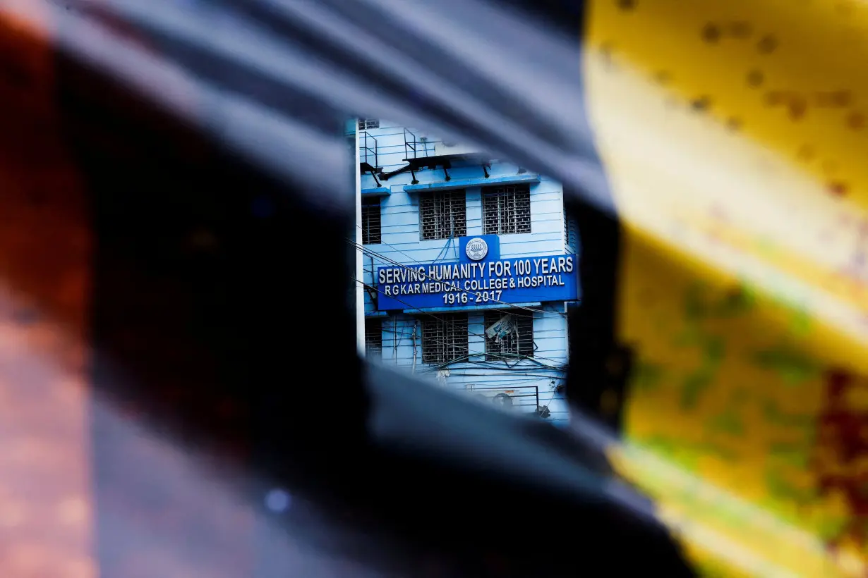 FILE PHOTO: A signboard of R G Kar Medical College and Hospital is seen through a poster hanging on a closed gate, in Kolkata