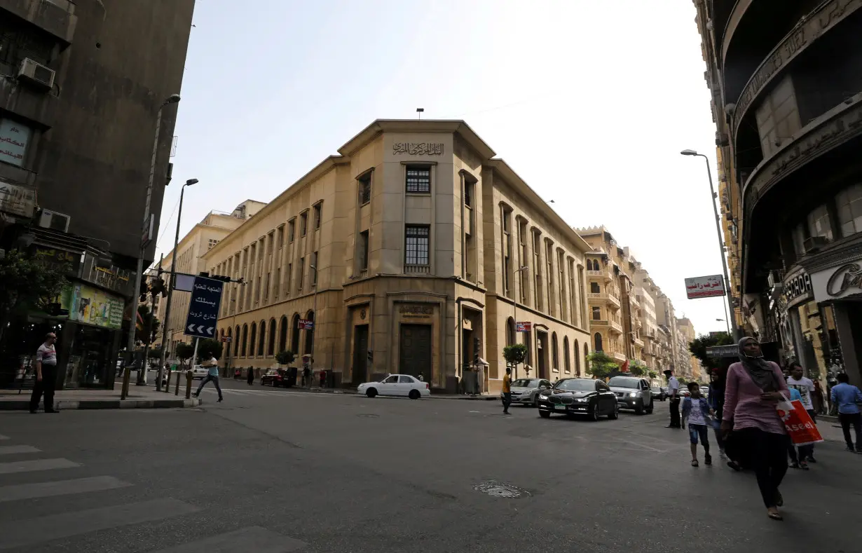 FILE PHOTO: Egyptians walk in front of the central bank in central Cairo