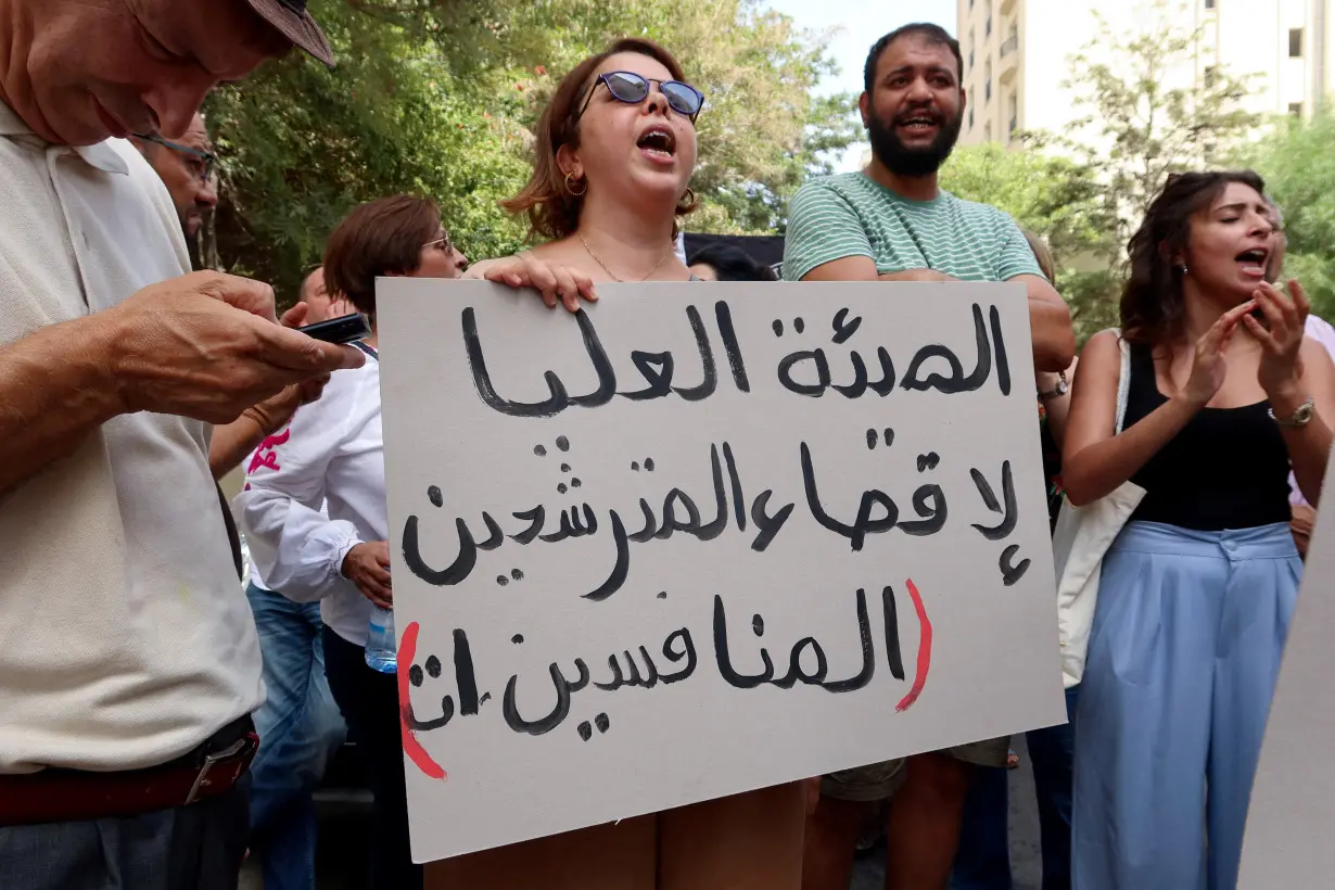 FILE PHOTO: A demonstrator carries a banner during a protest near the headquarters of the Electoral Commission in Tunis