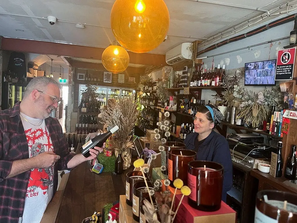 Liquor store P&V Wine + Liquor Merchants owner Louise Dowling serves a customer in Sydney